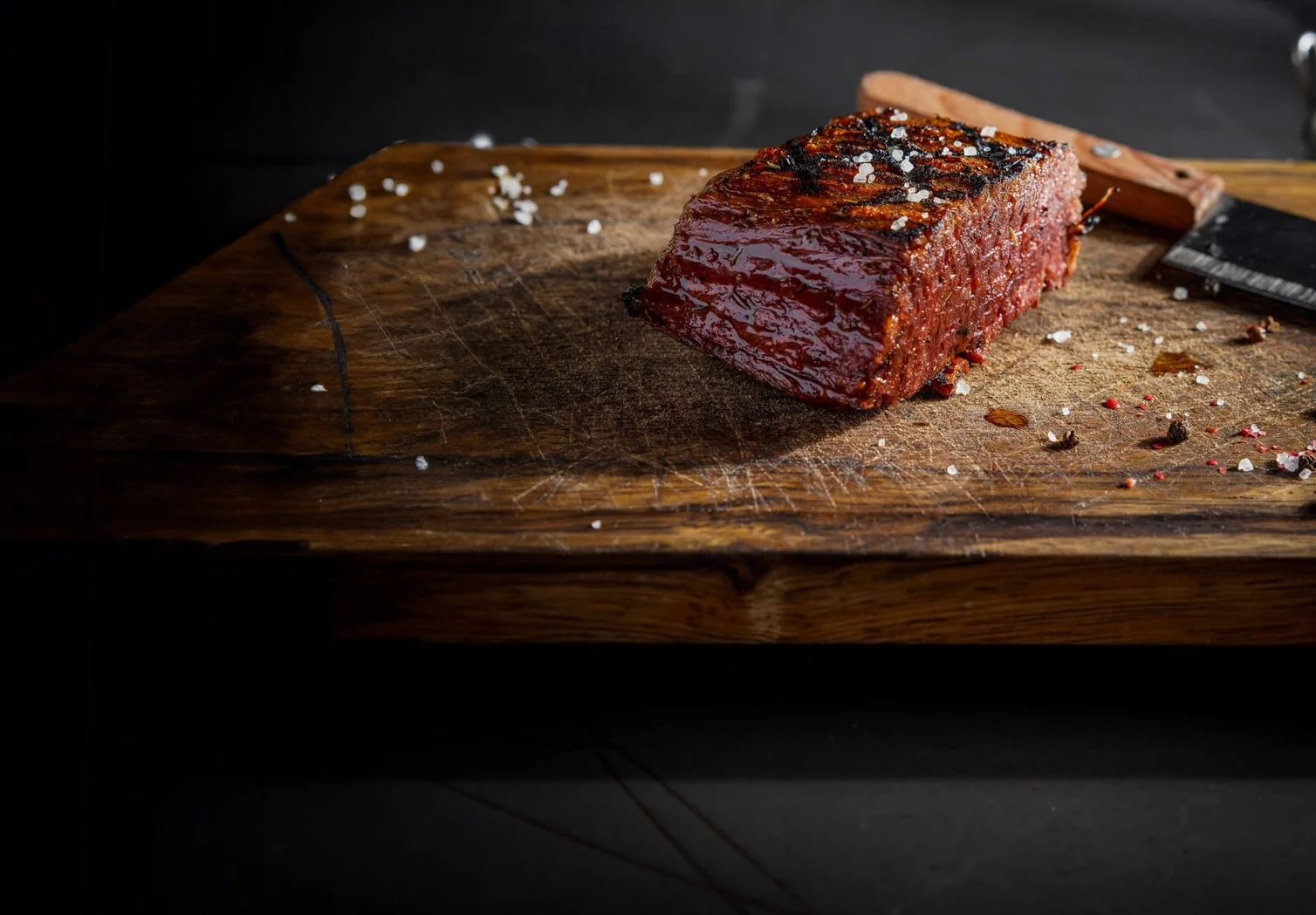 A seared Redefine Meat flank steak resting on a wooden board