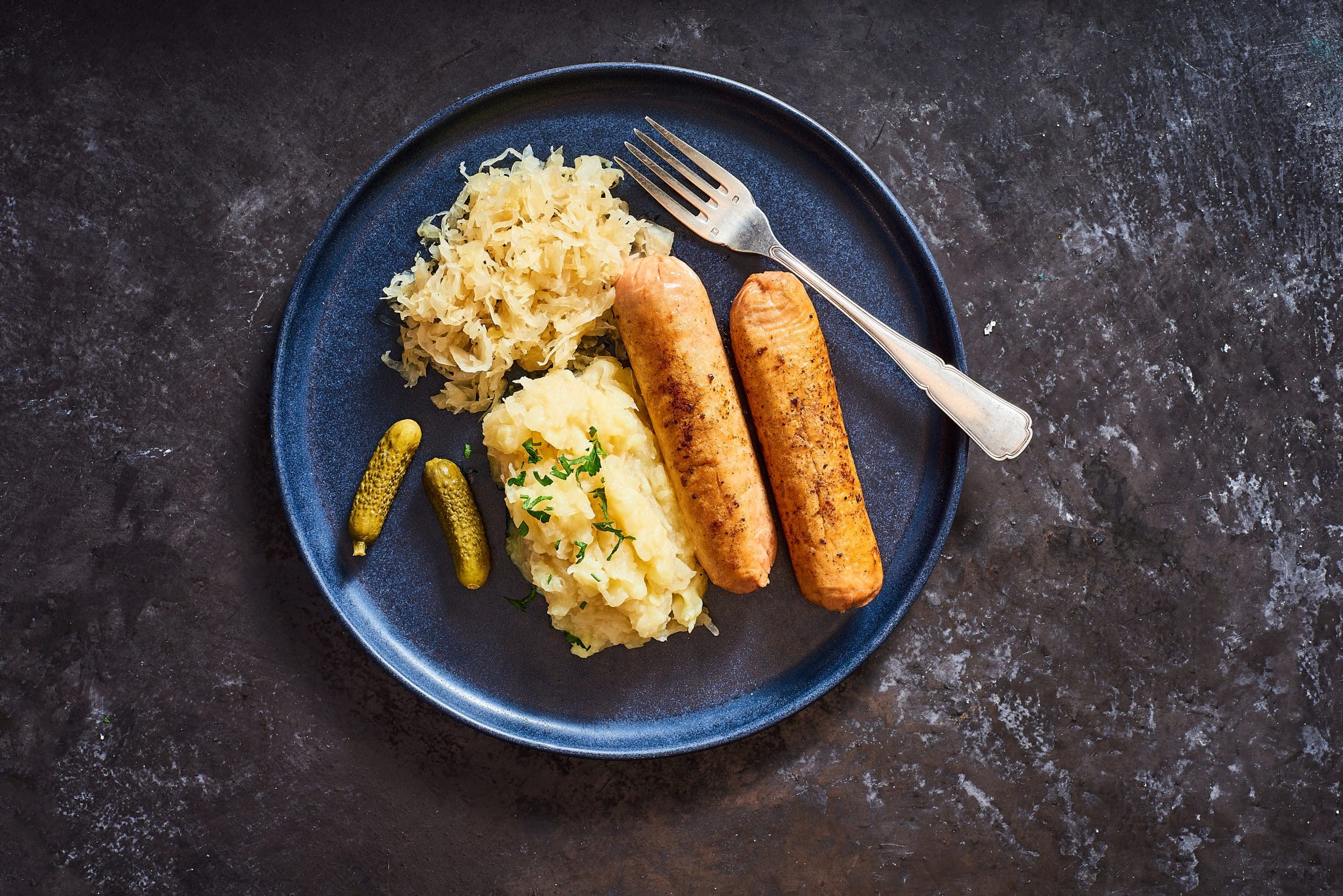 Bratwursts with Mashed Potatoes Alongside Sauerkraut, pickles and Mustard